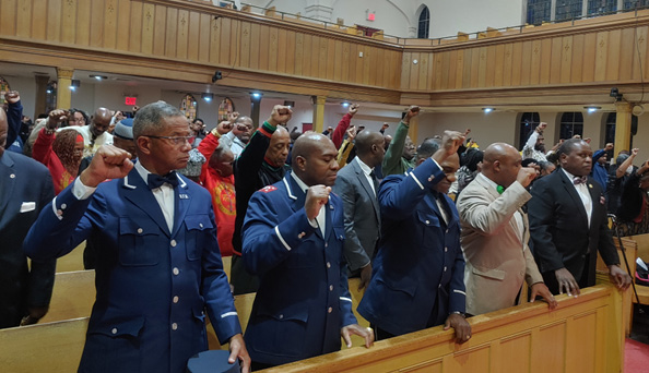 A group of people in blue jackets raising their hands

Description automatically generated