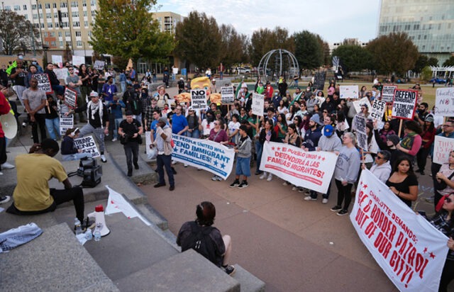 Federal immigration crackdowns escalate A group of people protesting AI-generated content may be incorrect.
