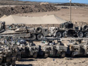 Trump ally seeks role in sprawling U.S. base project near Gaza A group of military vehicles parked in a dirt field AI-generated content may be incorrect.