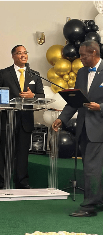 A person in a suit standing next to a person in a suit AI-generated content may be incorrect.