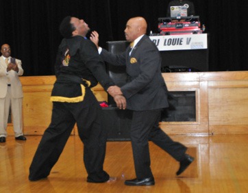 A person in black suit and yellow tie holding another person in black suit AI-generated content may be incorrect.