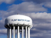 Settlement reached in Flint water crisis, but will payouts solve lingering concerns? A water tower with clouds in the background AI-generated content may be incorrect.