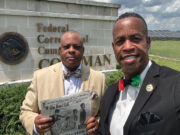 Nation of Islam reestablishes Prison Reform Ministry outreach at Coleman Correctional Complex Two adults dressed in formal attire stand outdoors in front of a sign for a federal correctional complex under a partly cloudy sky. Description generated by AI